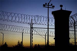 night sky, surveillance tower and fence with razor wire